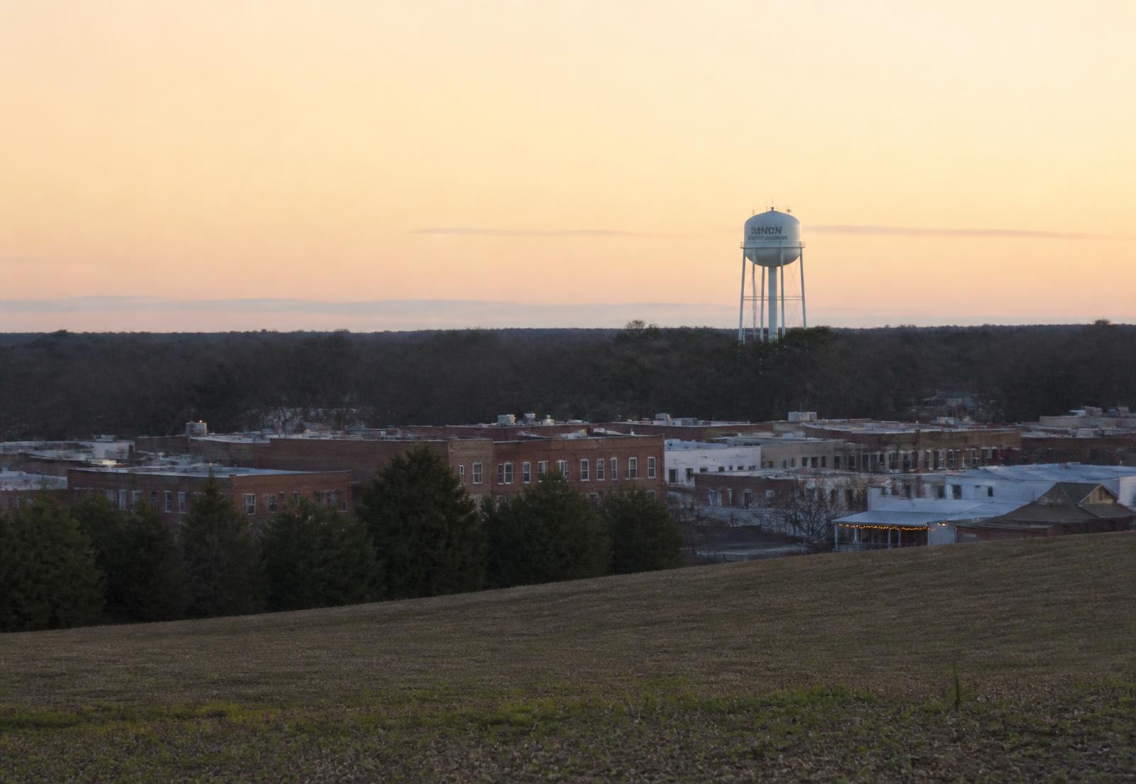 Union County, North Carolina at dusk: farmland edging into a small brick commercial district with a water tower beyond